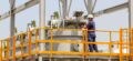 A maintenance guy stands on scaffolding and screws around on a backwash filter - FAUDI service