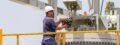 Assembly employee who is on a filter unit and adjusts the unit