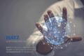 Hand, die nach einer blau leuchtenden Weltkugel greift, die ein Netzwerk darstellt, Firmen der WATZ Gruppe aufgelistet